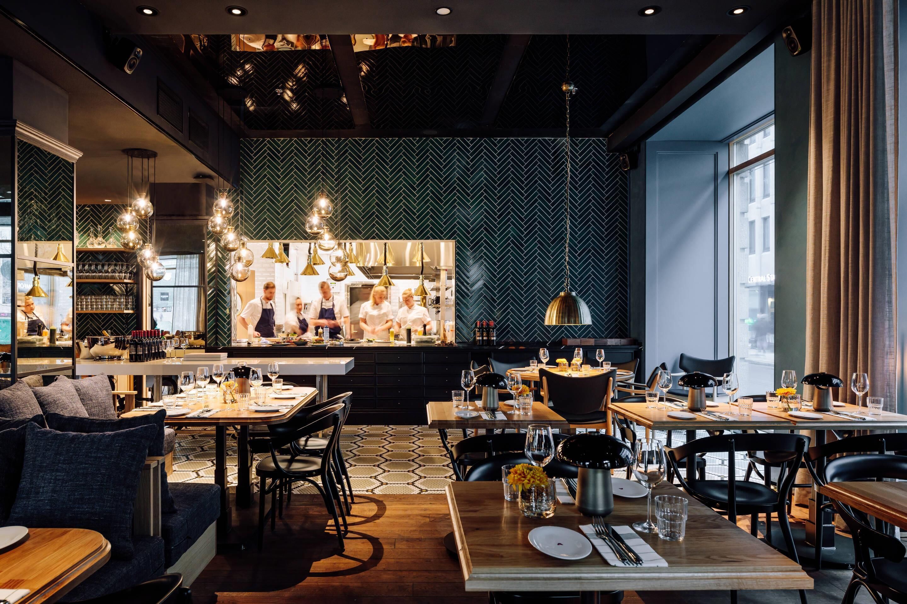 Un interior de restaurante moderno con una barra central, mesas para comer y un suelo con estampado.