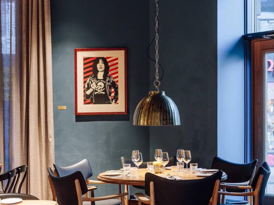 A dining area with a round table, chairs, and a hanging light fixture.