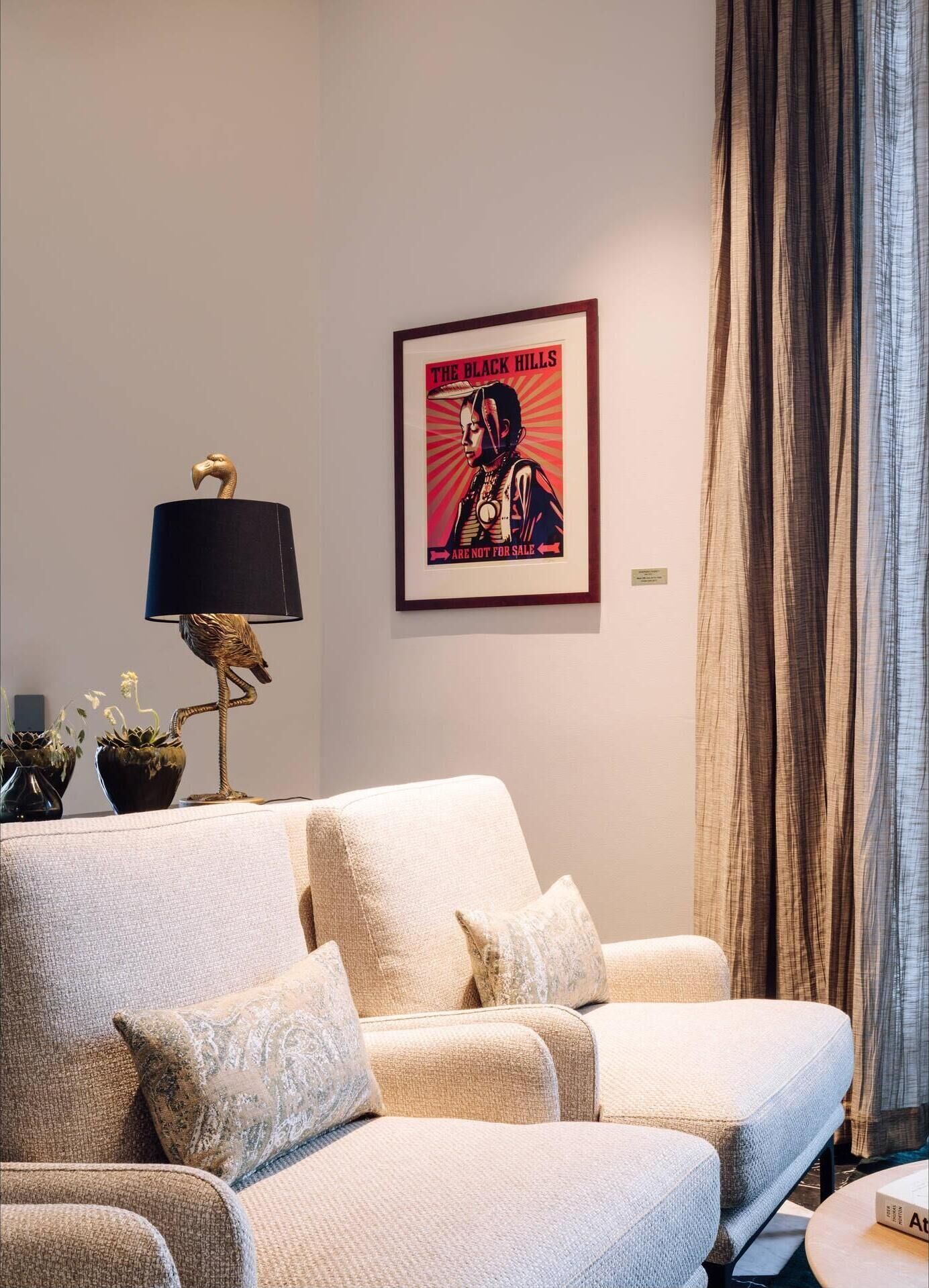 A living room with a sofa, a lamp, and a framed poster on the wall.