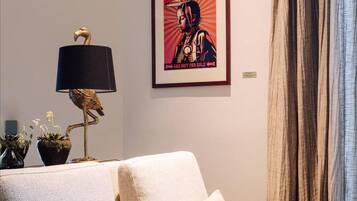 A living room with a sofa, a lamp, and a framed poster on the wall.