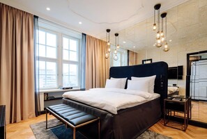 Una habitación de hotel moderna con una cama grande, mesitas de noche, un banco y un televisor.