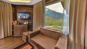 Un área de estar acogedora con un sofá, una televisión y vistas a las montañas.