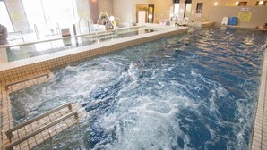 An indoor swimming pool with clear water, a tiled floor, and a glass barrier. - Kur and Hotel Shinshu (Shiojiri)