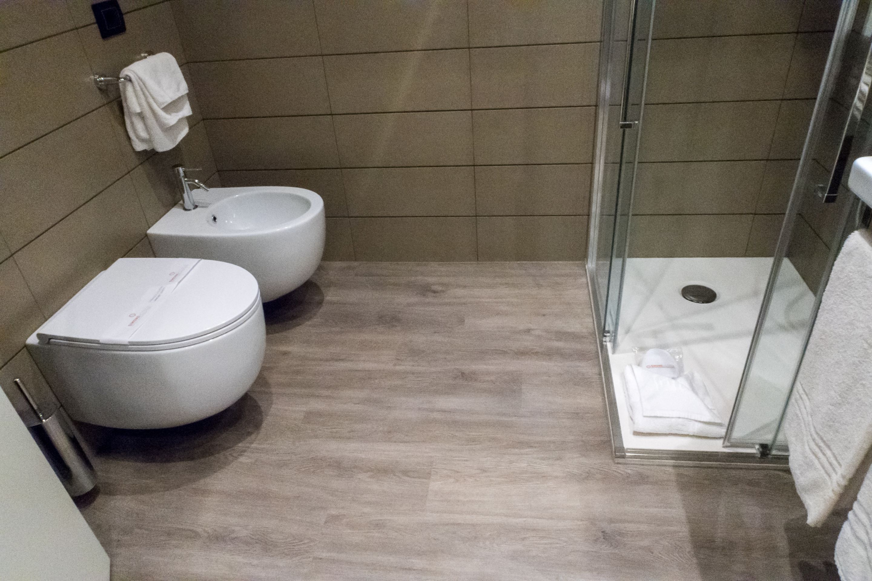 A modern bathroom with a toilet, bidet, and glass-enclosed shower.