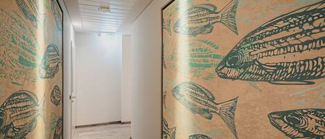 A hallway with patterned wallpaper and wooden flooring.