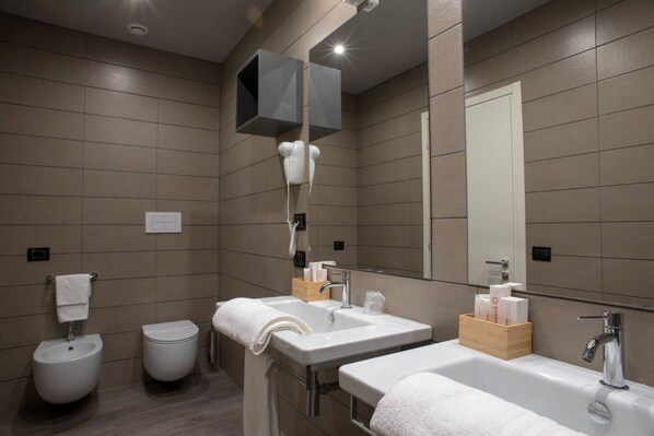 Un bagno moderno con due lavabi, un bidet e uno specchio.