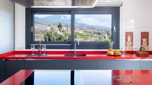 Eine moderne Küche mit roter Arbeitsplatte, einem großen Fenster mit Blick auf die Stadt und einer Edelstahl-Dunstabzugshaube.