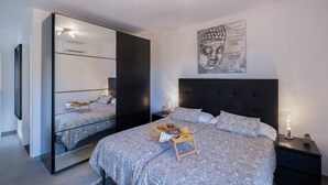 Ein modernes Schlafzimmer mit einem großen Bett, einem Nachttisch mit Lampe und einem Wandbild.