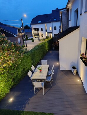 A patio with a table and chairs, a Buddha statue, and a hedge. - House Lorea near Lake Bütgenbach (Bütgenbach)