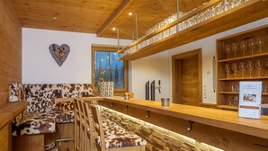 A bar area with wooden furniture and shelves of glasses. - Hotel Rupertihof (Ainring)