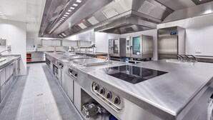 A modern kitchen with stainless steel appliances, a large sink, and overhead ventilation. - Hotel Rupertihof (Ainring)