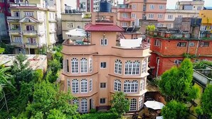 Un edificio de varios pisos con un patio central, rodeado de vegetación y otros edificios residenciales.