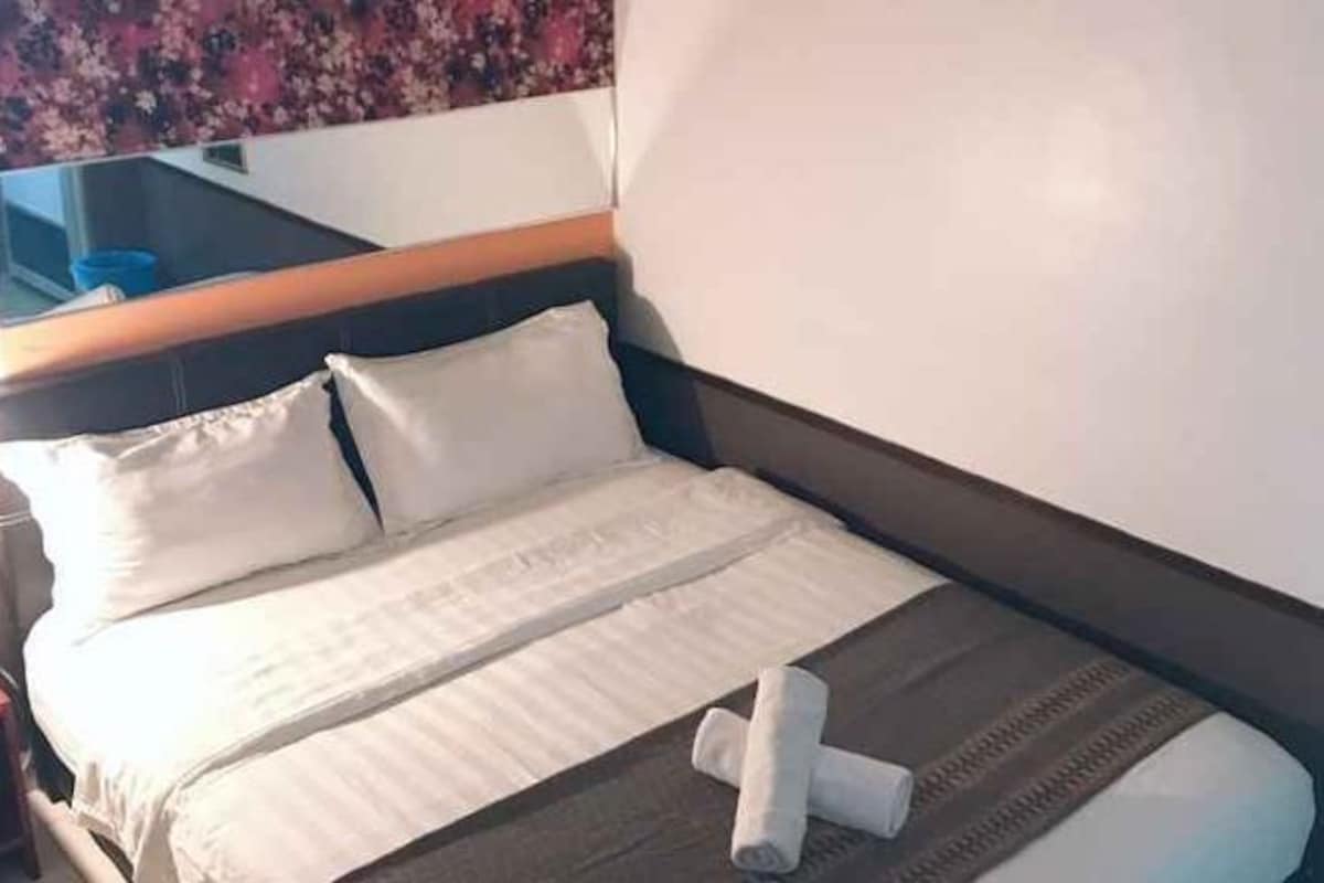 Une chambre d’hôtel avec un lit, des oreillers, une couverture et une serviette enroulée.