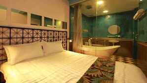 Une chambre d’hôtel avec un lit, un grand miroir, une baignoire et une fenêtre avec des rideaux.