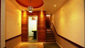 Un couloir avec un lambris en bois, un escalier et une porte donnant sur une pièce.