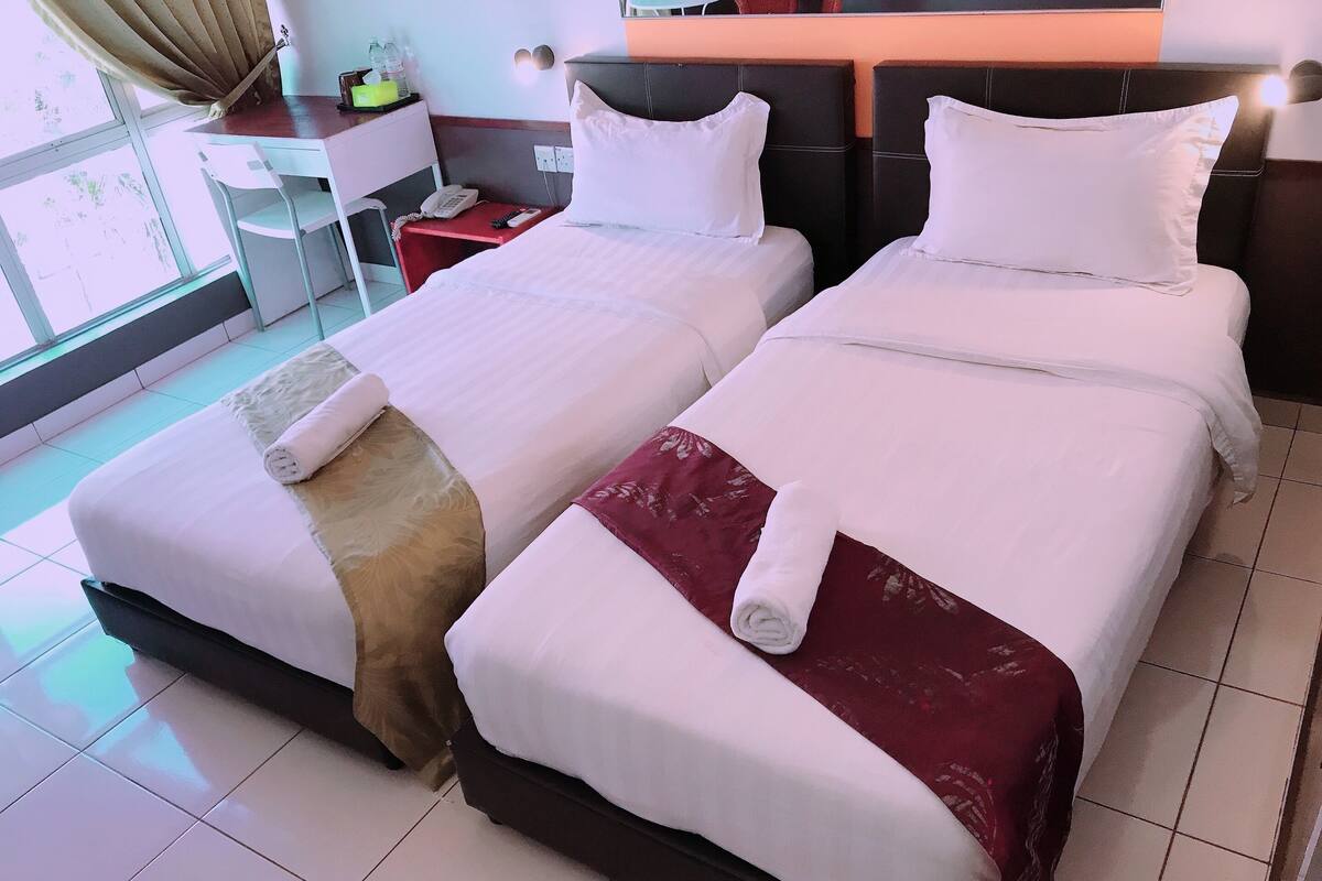 A hotel room with two beds, a desk, and a chair.