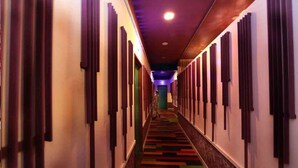 Un couloir d’hôtel avec un tapis à motifs, des lambris en bois sur les murs et un luminaire au plafond.
