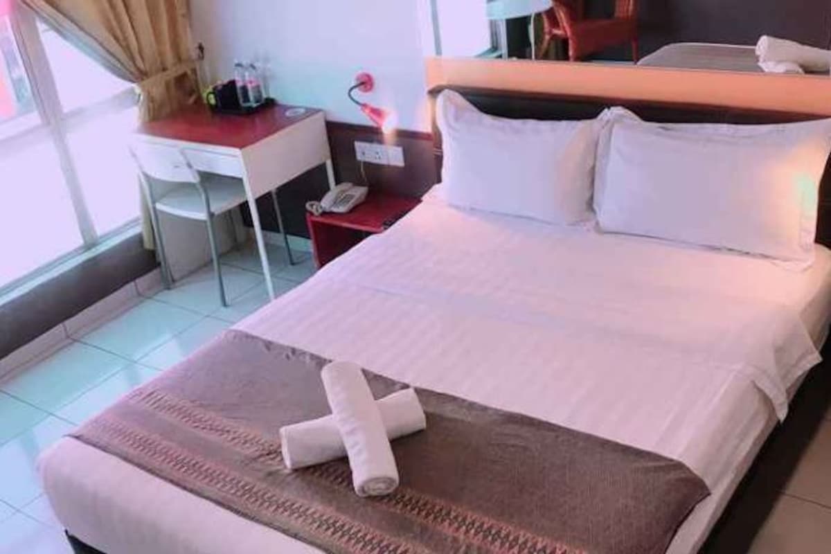 Une chambre d’hôtel avec un lit, un bureau, une chaise et une fenêtre.