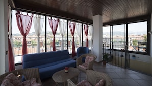 A balcony with a blue sofa, wicker chairs, and a small table with a flower. - Alex e Angie (Bergamo)