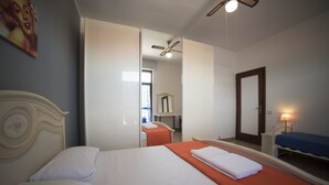 A hotel room with a bed, a bedside table, a mirror, a ceiling fan, and a window. - Alex e Angie (Bergamo)