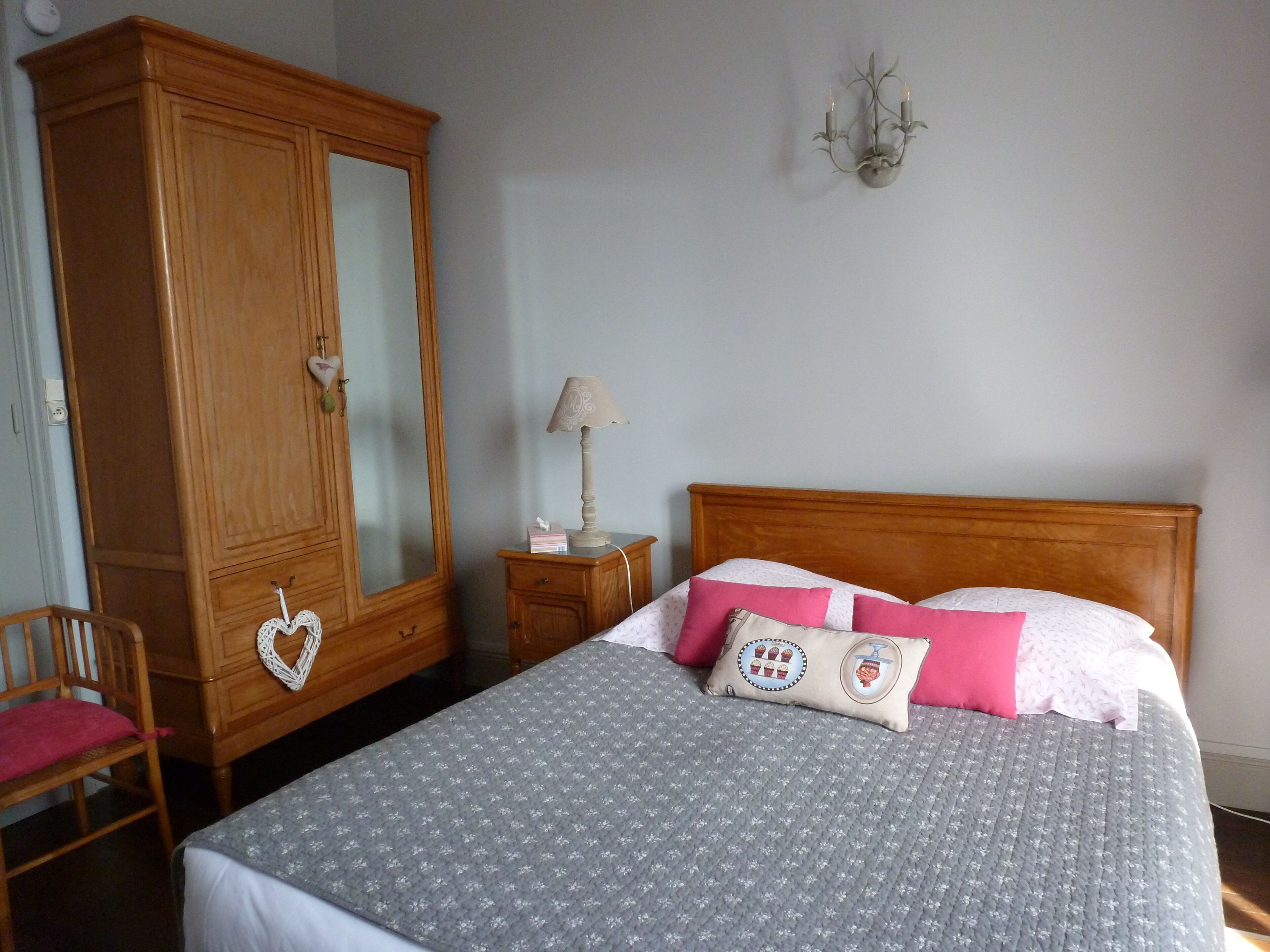 Une chambre à coucher avec une grande armoire en bois, un lit avec une literie à motifs et une table de chevet avec une lampe.