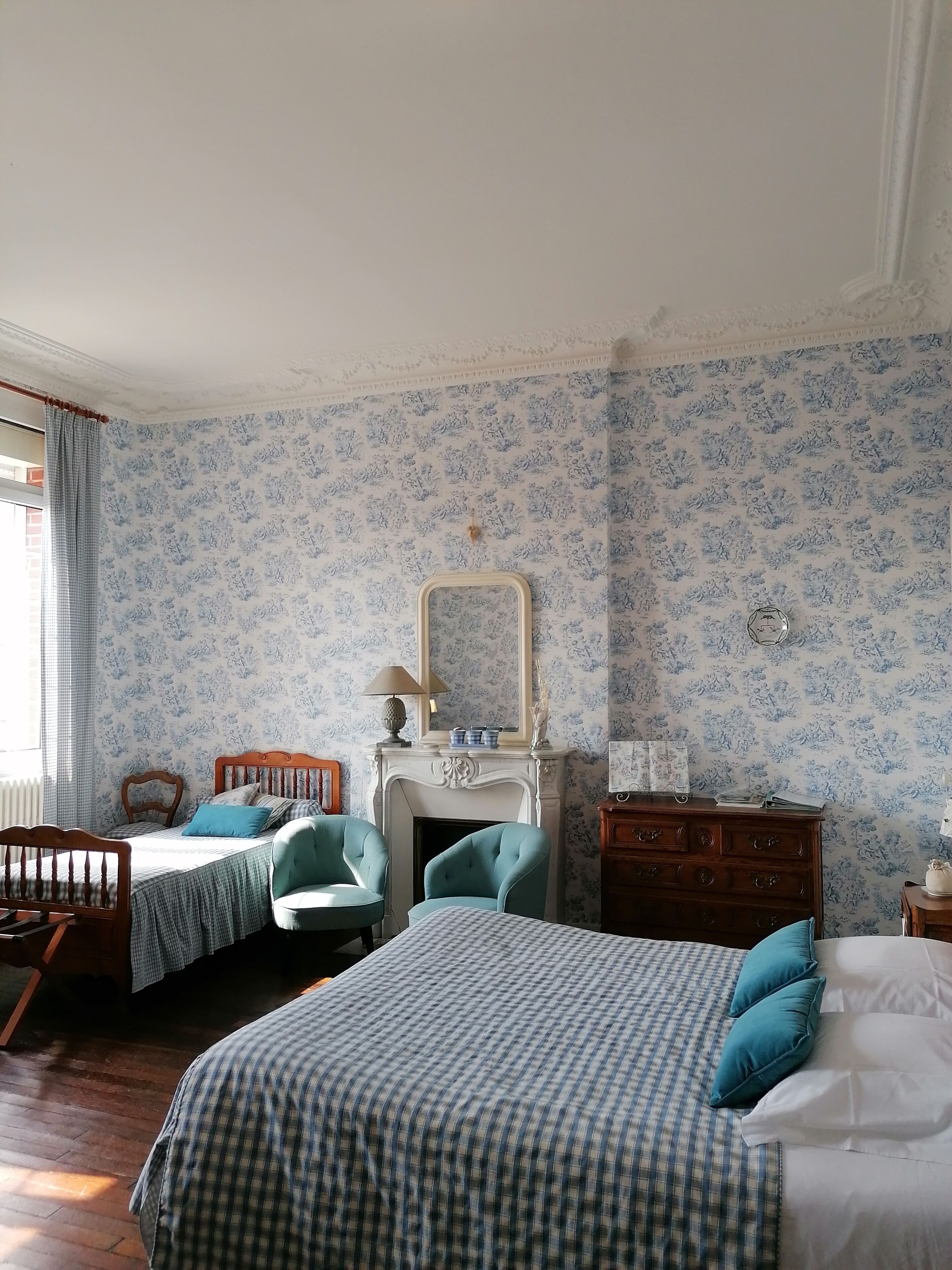 Une chambre avec deux lits, une cheminée et un miroir.