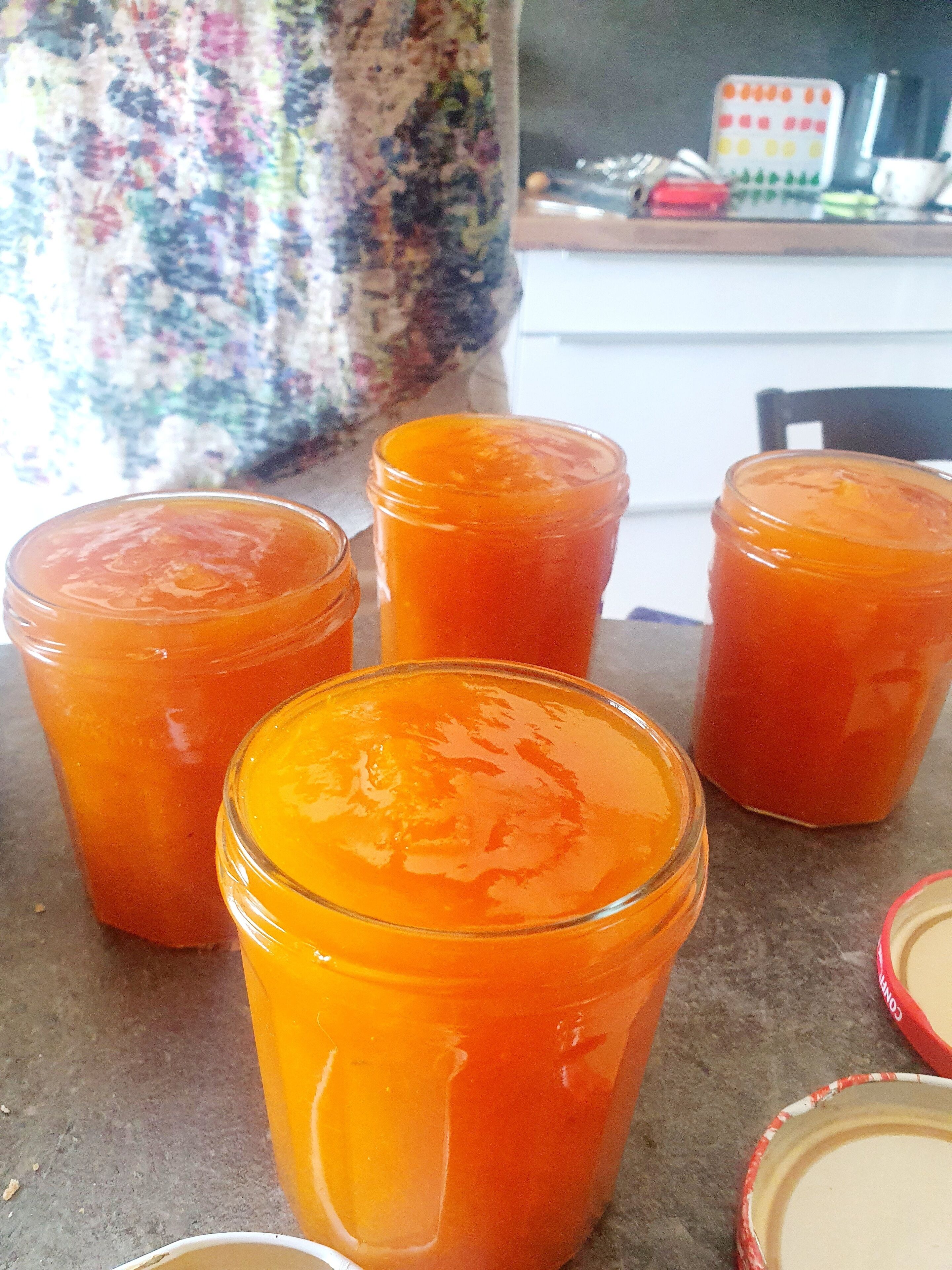 Quatre bocaux en verre contenant une substance orange sont posés sur une table.