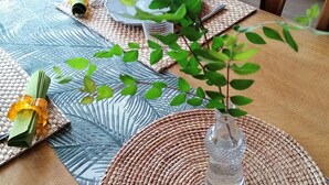 A dining table with a woven placemat, a glass vase with a plant, and a plate with a fork. - Ferme de Bonavis - Chambres d'Hôtes (Banteux)