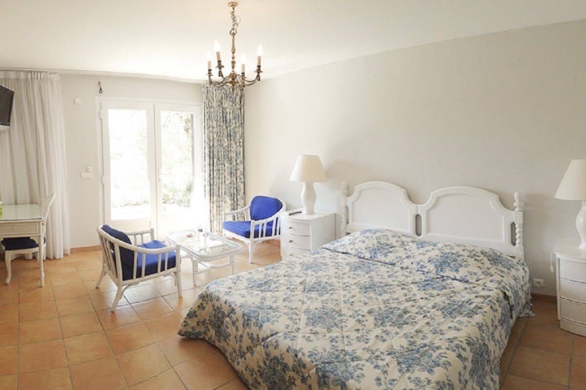 Een slaapkamer met een bed, een stoel, een bureau en een kroonluchter.