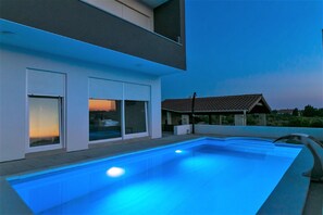 Een modern huis met een zwembad, grote ramen en een pannendak.