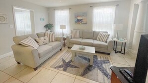 A living room with two sofas, a coffee table, a TV, and a ceiling fan.