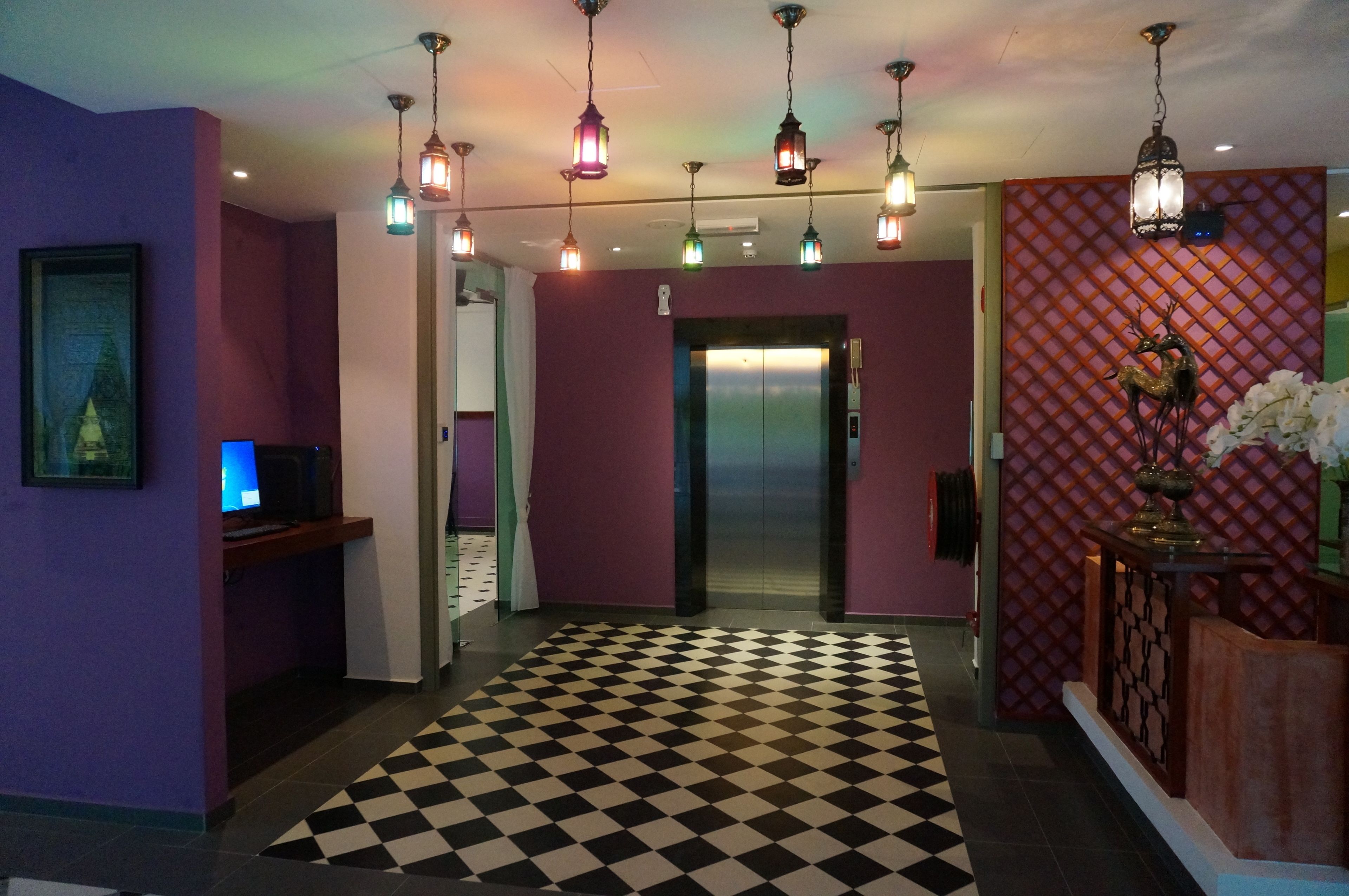 A lobby with purple walls, a checkered floor, and multiple hanging lights.