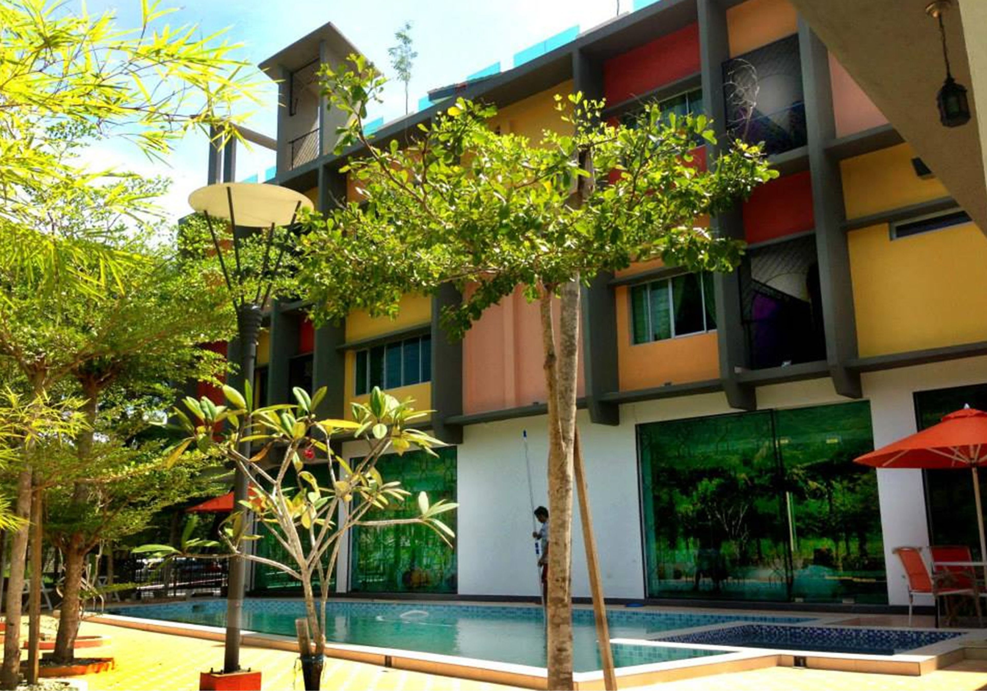 A modern building with a pool area, surrounded by potted plants and outdoor seating.