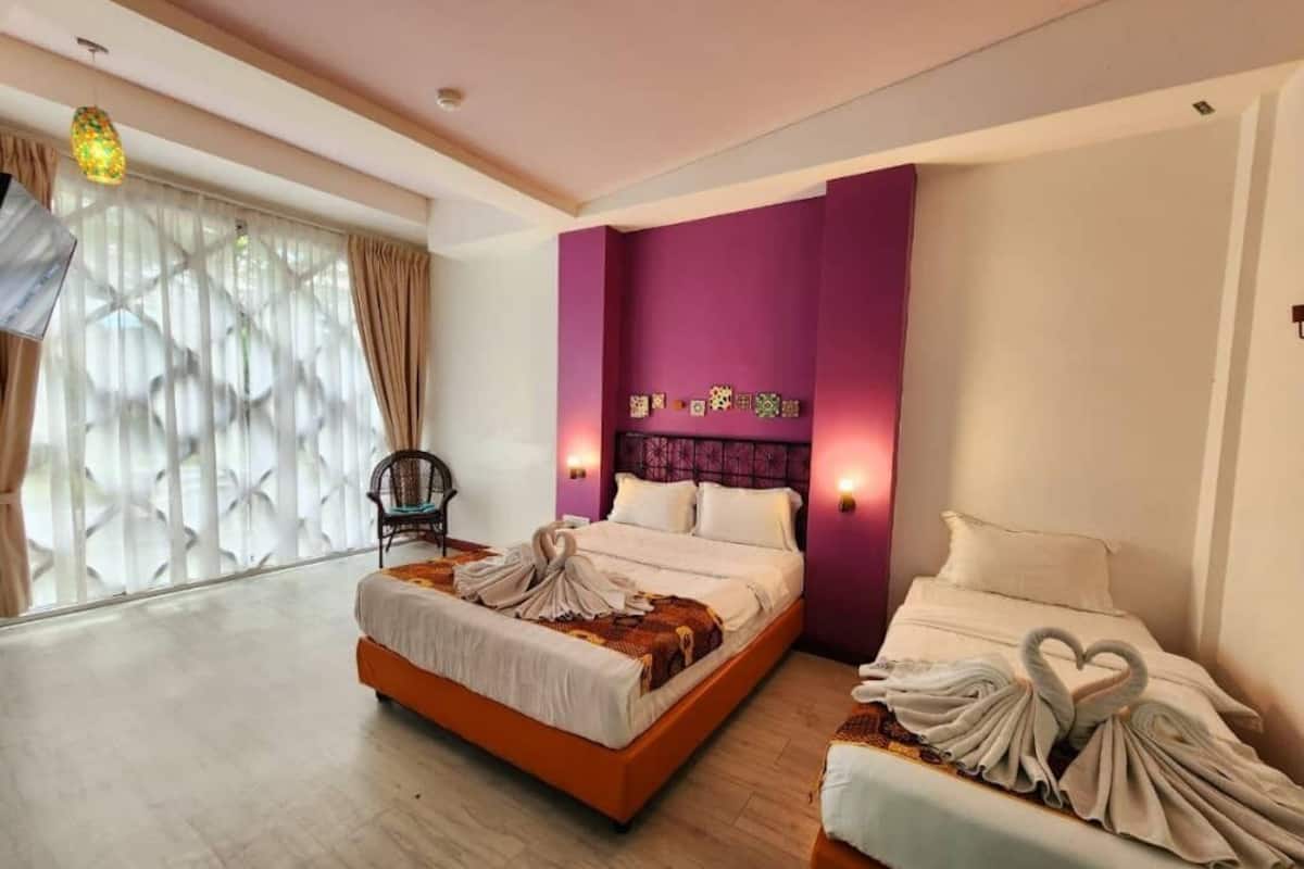 Quarto de hotel com uma cama grande, uma cama menor e uma cadeira.