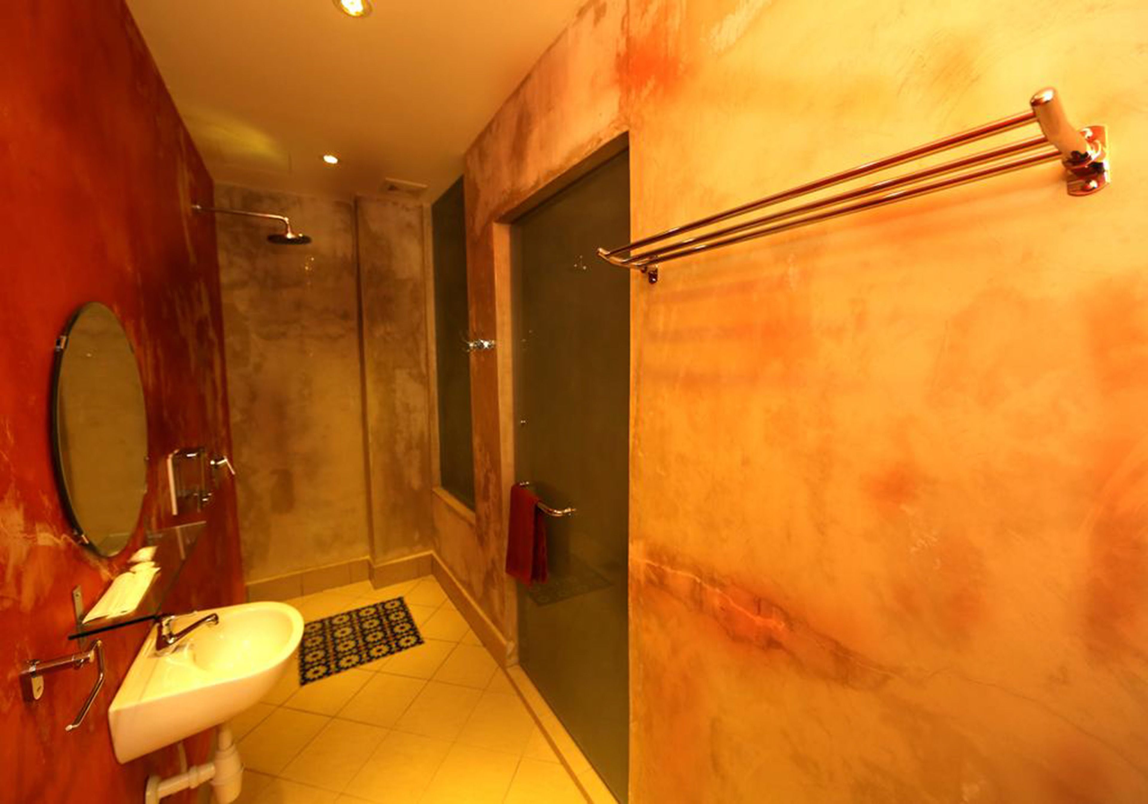 Een badkamer met een wastafel, spiegel, douche en handdoekrek.