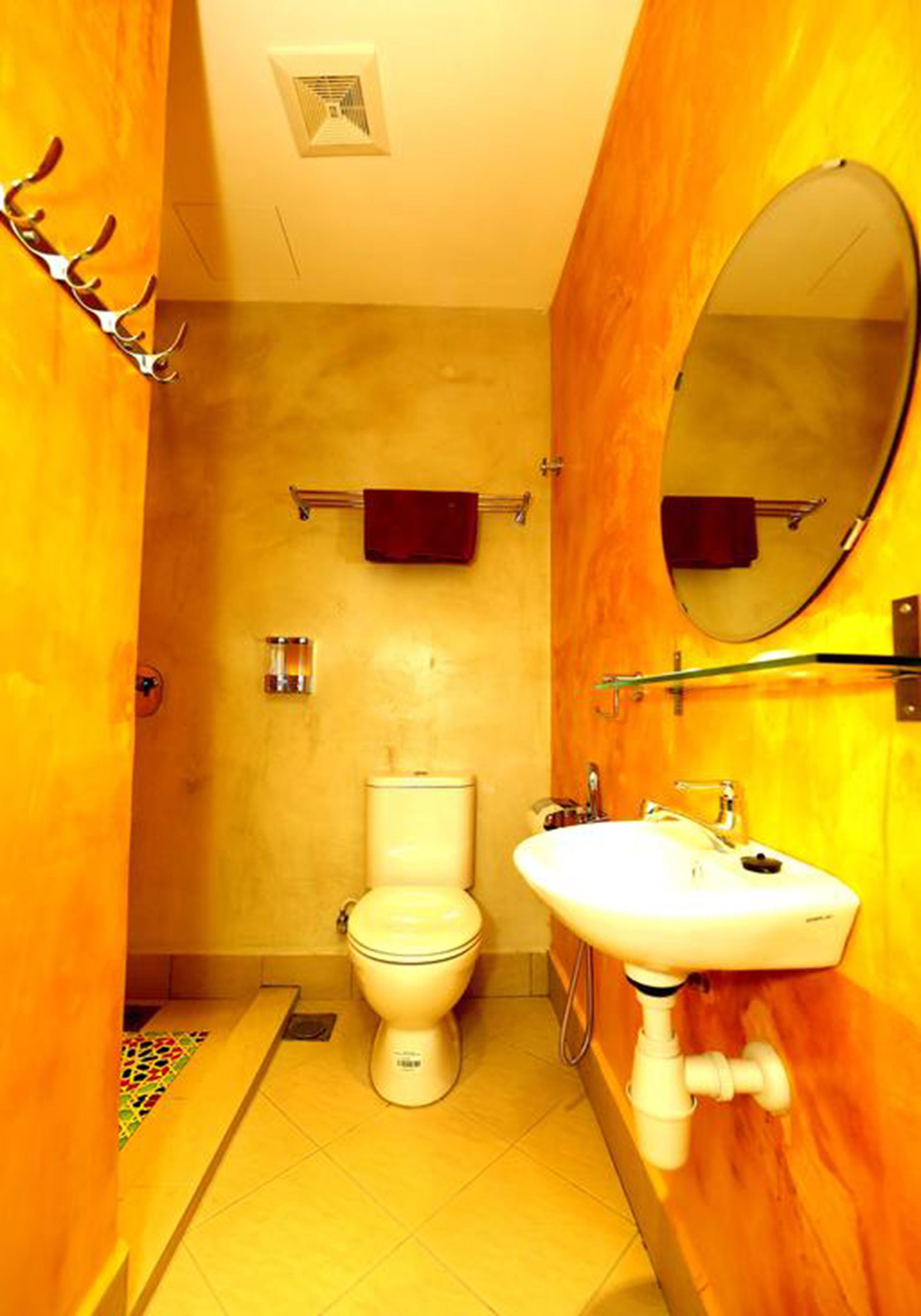 A bathroom with a toilet, sink, and mirror.