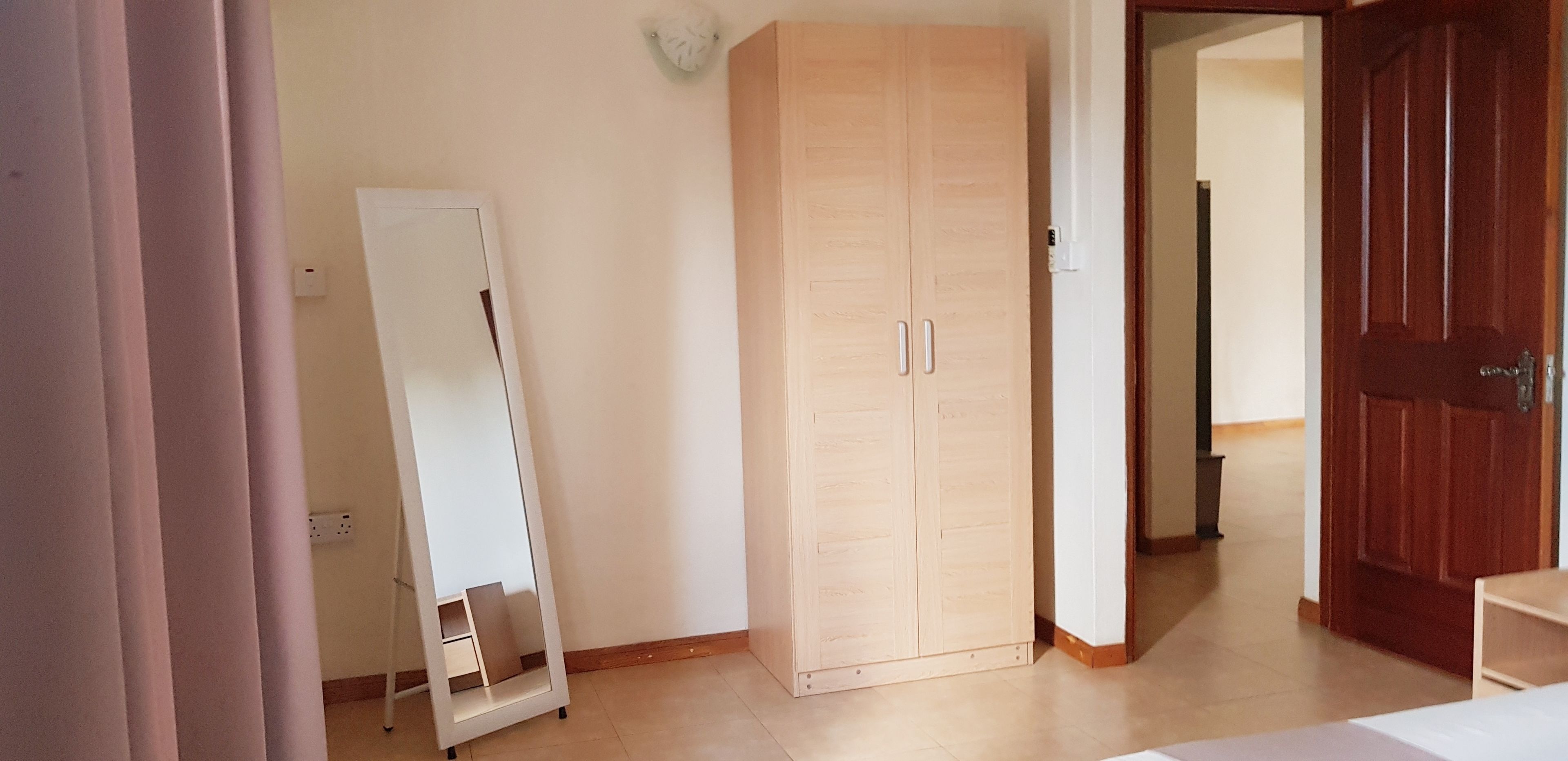 Een kamer met een kast, een spiegel en een deur.