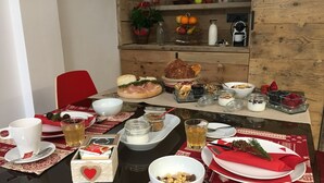 A dining table set with various food items, including bread, fruits, and condiments. - Atmosphere di Montagna (Vermiglio)