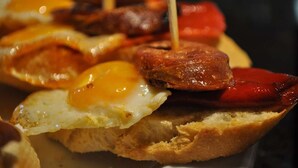 A close-up of a breakfast dish with eggs and sausages on toast. - Hostal La Tablada (Navaleno)