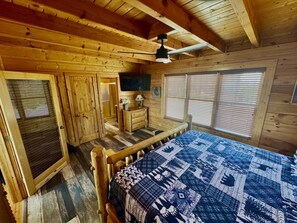 Ein Schlafzimmer einer Holzhütte mit Bett, Kommode und Deckenventilator.