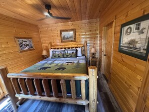 A wooden cabin interior with a bed, a framed picture on the wall, and a window. - HEAVENLY DAZE — THREE KING SUITES, THREE LIVING AREAS & ROOM FOR 12 (Sevierville)