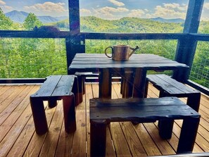 A wooden deck with a table and benches, overlooking a green landscape. - HEAVENLY DAZE — THREE KING SUITES, THREE LIVING AREAS & ROOM FOR 12 (Sevierville)