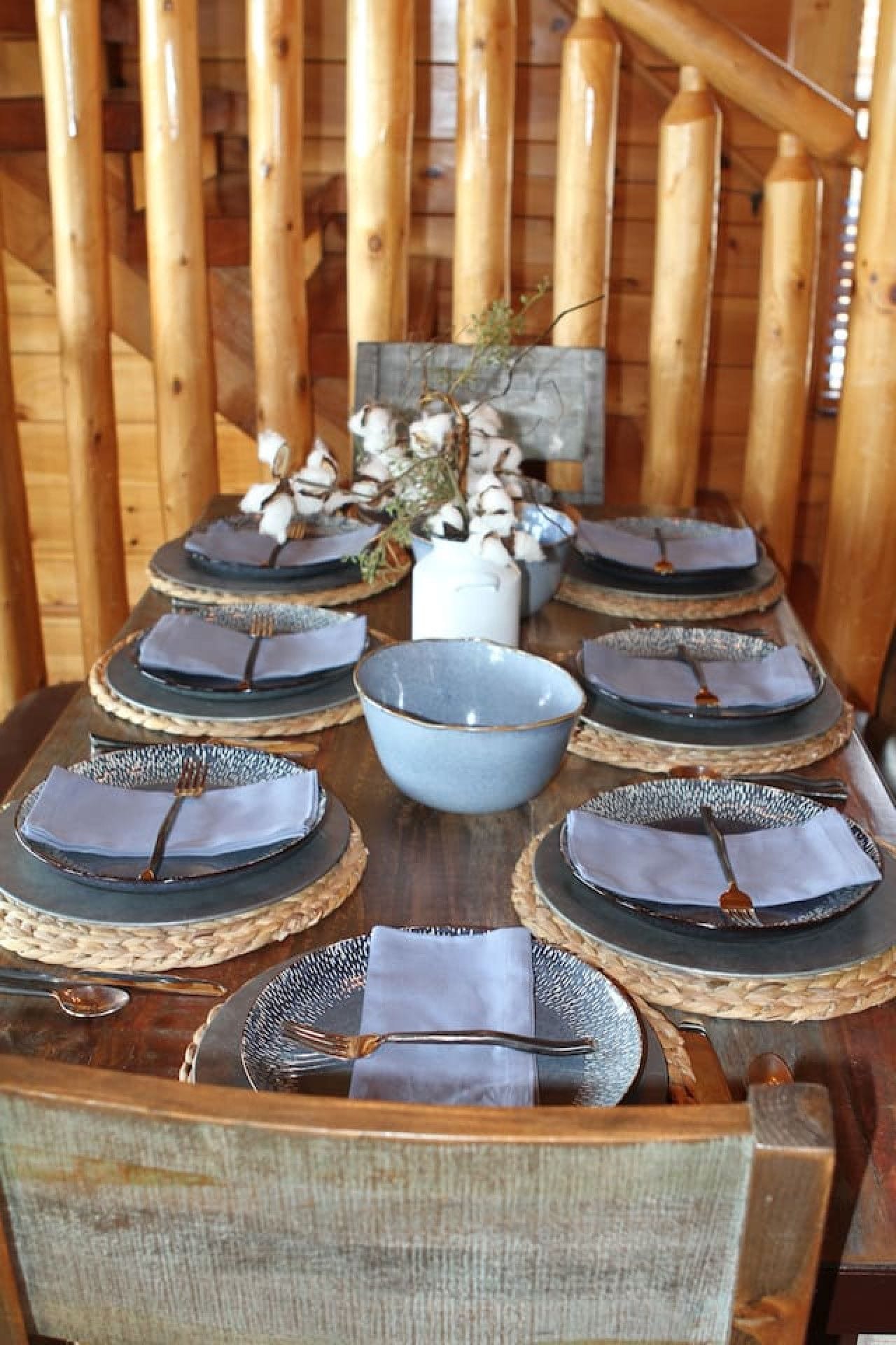 A wooden dining table set with plates, bowls, and cutlery.