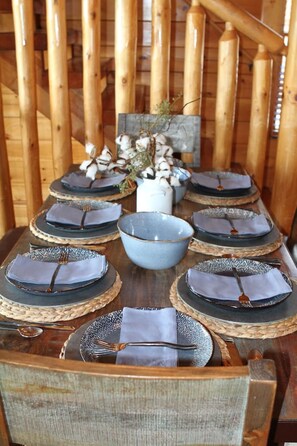Una mesa de comedor de madera dispuesta con platos, tazones y cubiertos.