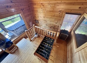 Un intérieur en bois avec un baby-foot, une fenêtre et un escalier.