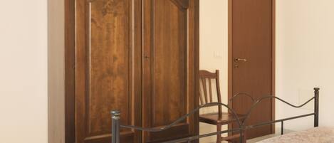 A bedroom with a bed, a wooden wardrobe, and a door.