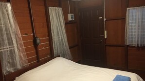 Een hotelkamer met een bed, een houten garderobe en een deur.