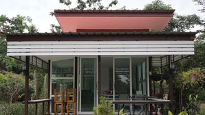 Een modern gebouw met glazen entree, houten stoelen en potplanten.