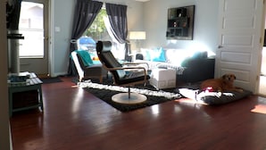 A living room with a black leather chair, a white ottoman, a black sofa, and a dog resting on a cushion. - Recently renovated, new front porch and walk-able to the town of Black Mountain  (Black Mountain)