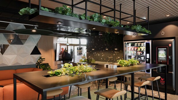 A modern bar area with a long counter, bar stools, and a seating area with orange sofas. - Citybox Bergen Danmarksplass (Bergen)